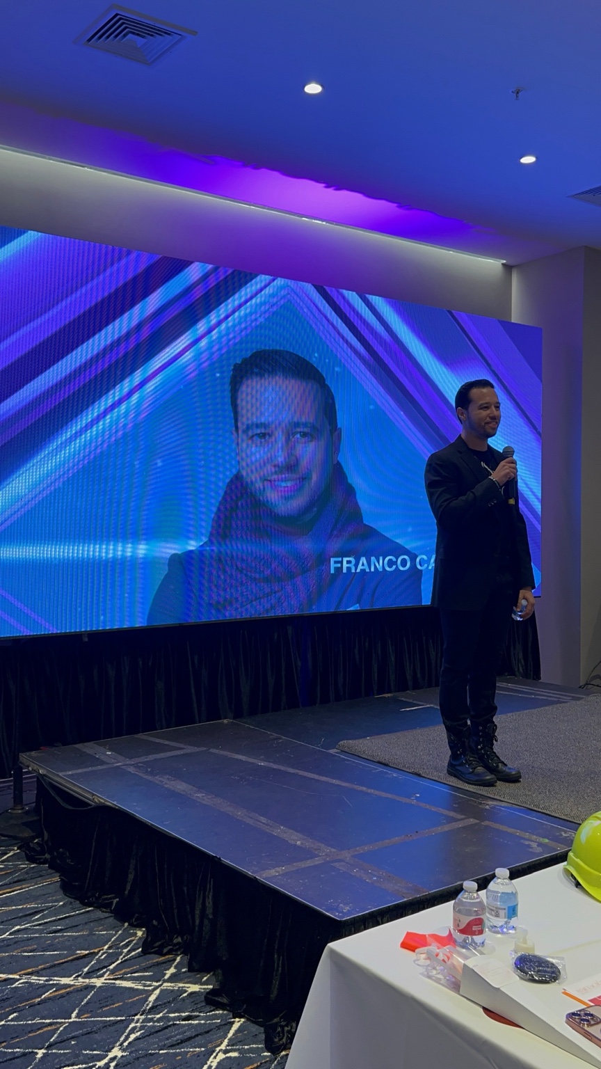 Franco speaking to a large audience from a stage